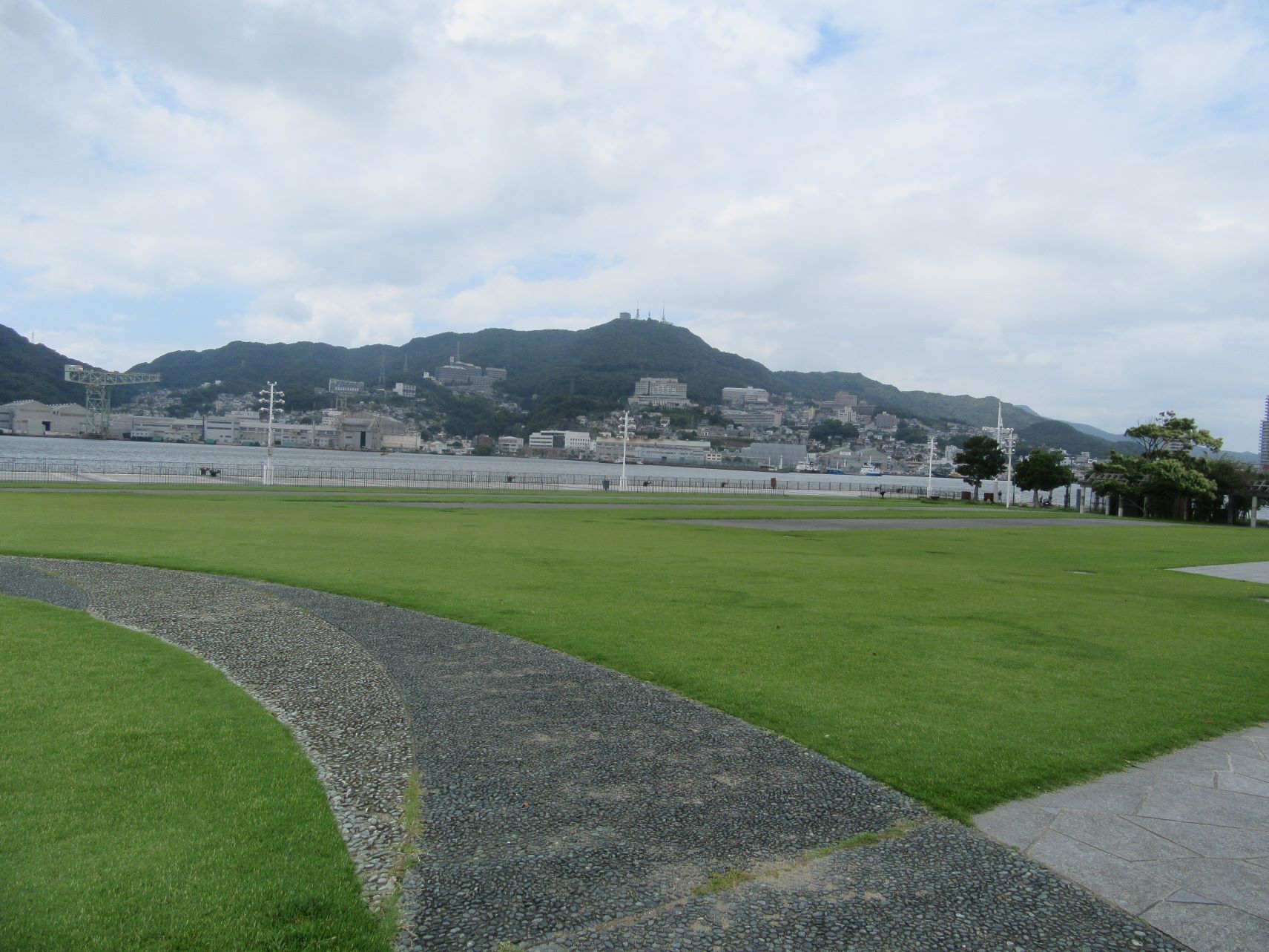 長崎市・長崎水辺の森公園の風景と、背景のジャイアント・カンチレバークレーンや稲佐山。