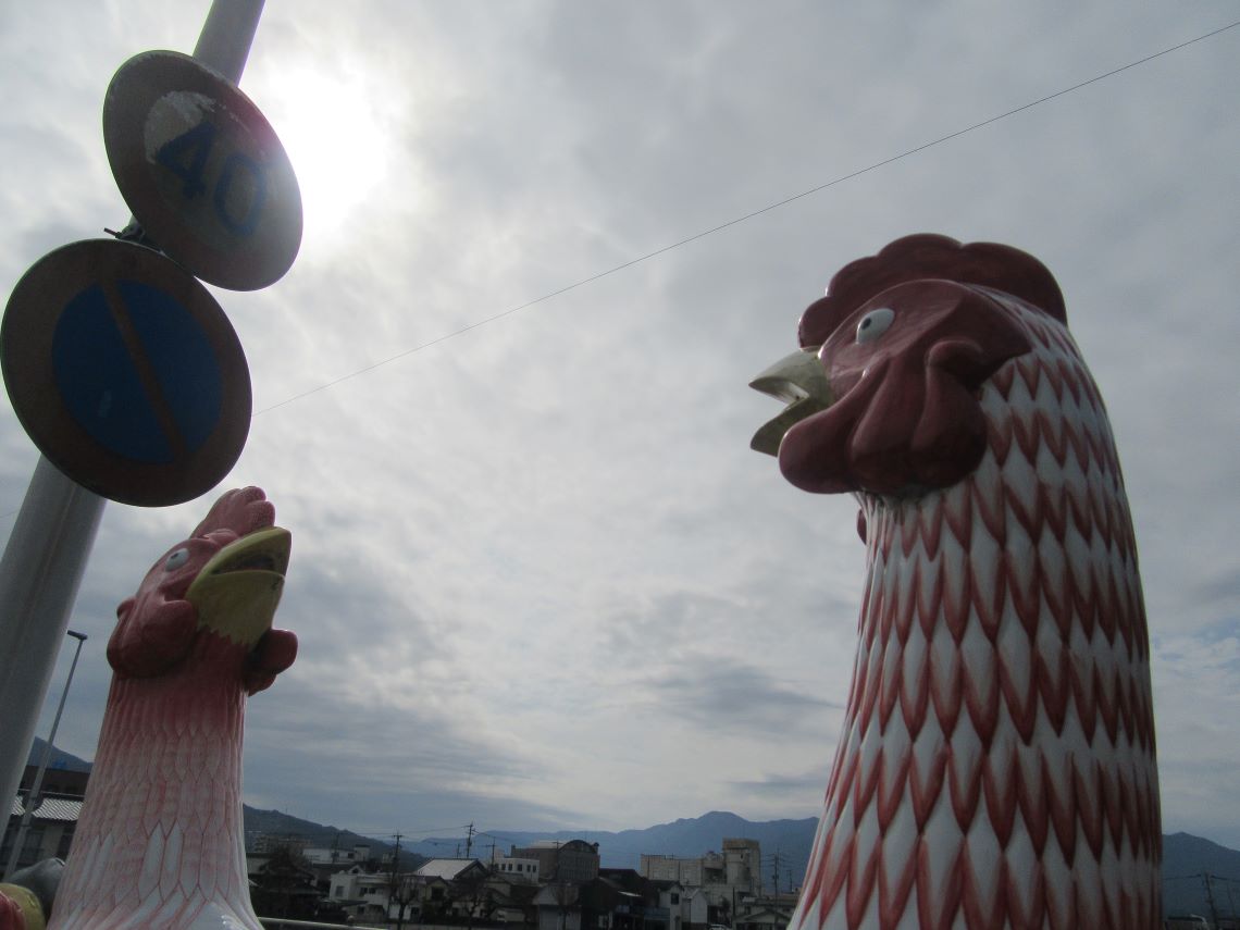 佐賀県伊万里市にある伊萬里神社の『伊万里焼の夫婦鶏像』と太陽。