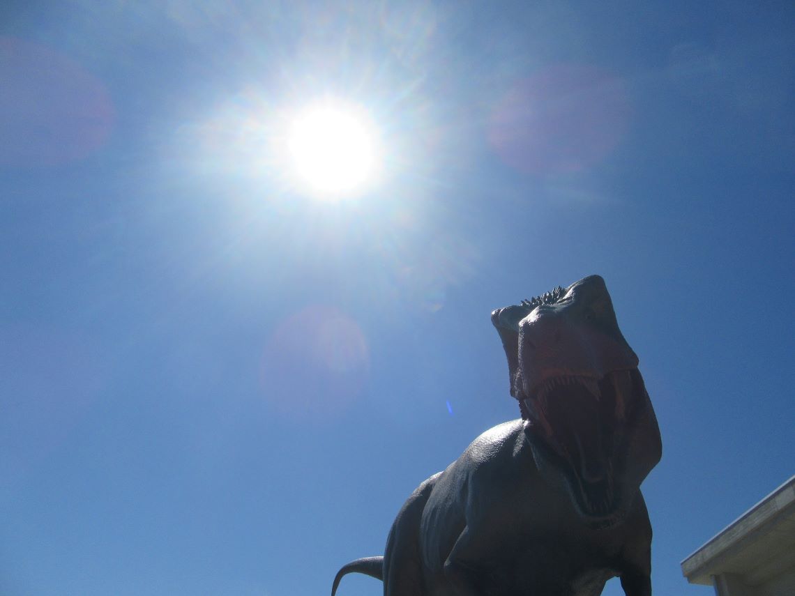 長崎市の長崎のもざき恐竜パークで撮影した、迫力ある恐竜のオブジェと太陽。