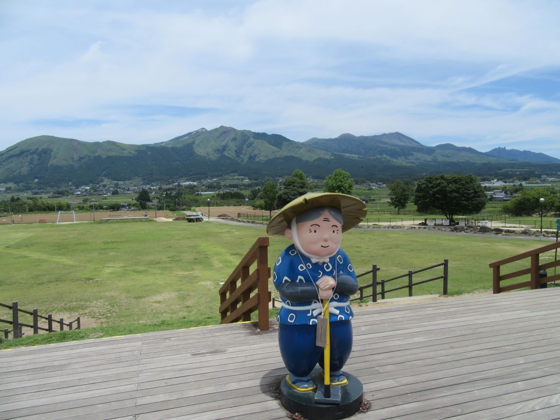 熊本県阿蘇・南阿蘇村にある道の駅・『あそ望の郷くぎの』で撮影した、おばあちゃんのオブジェの後ろにある阿蘇の山々。
